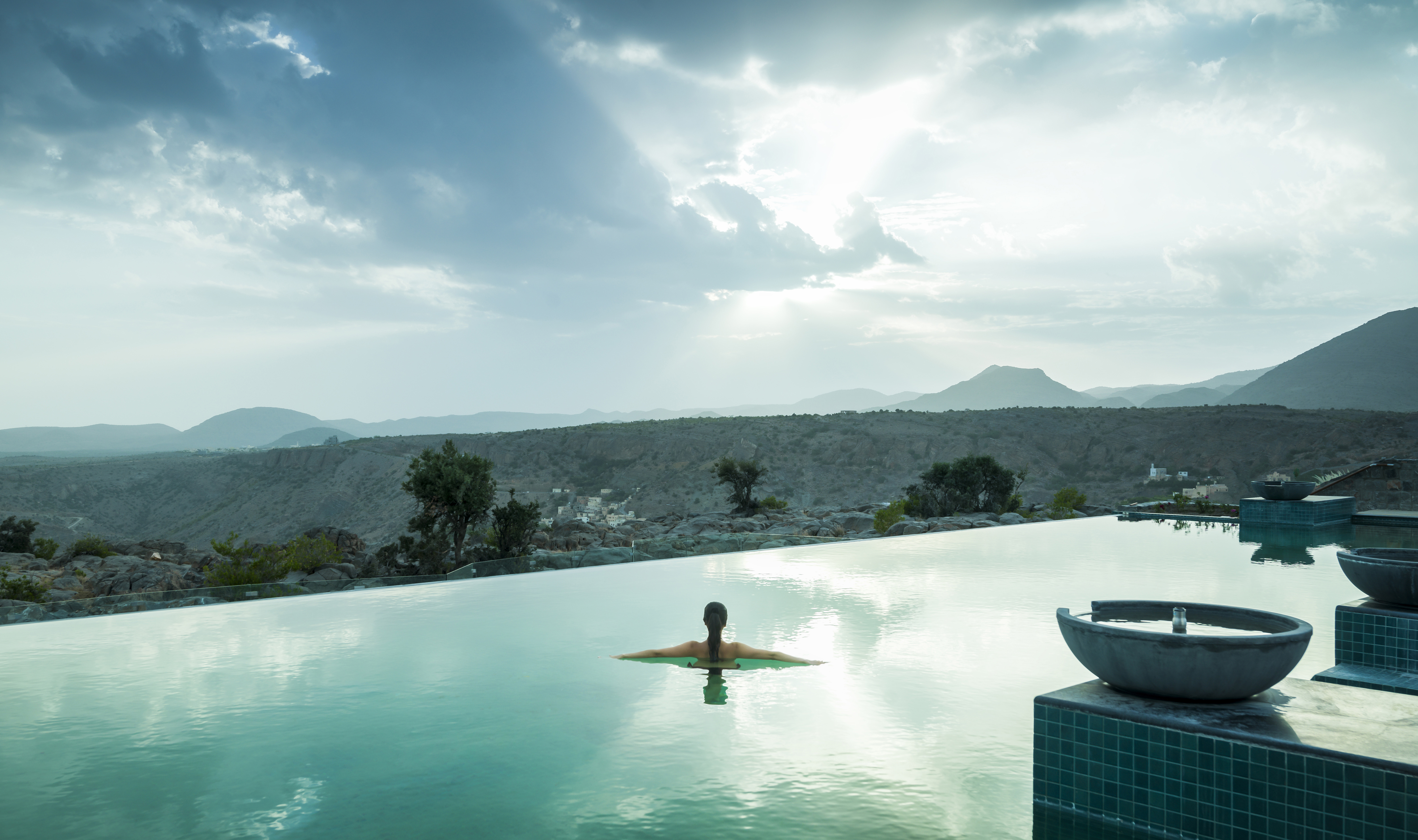 A woman relaxes and takes in the incredible views from the infinity pool at Anantara al Jabal al Akhdar, Oman