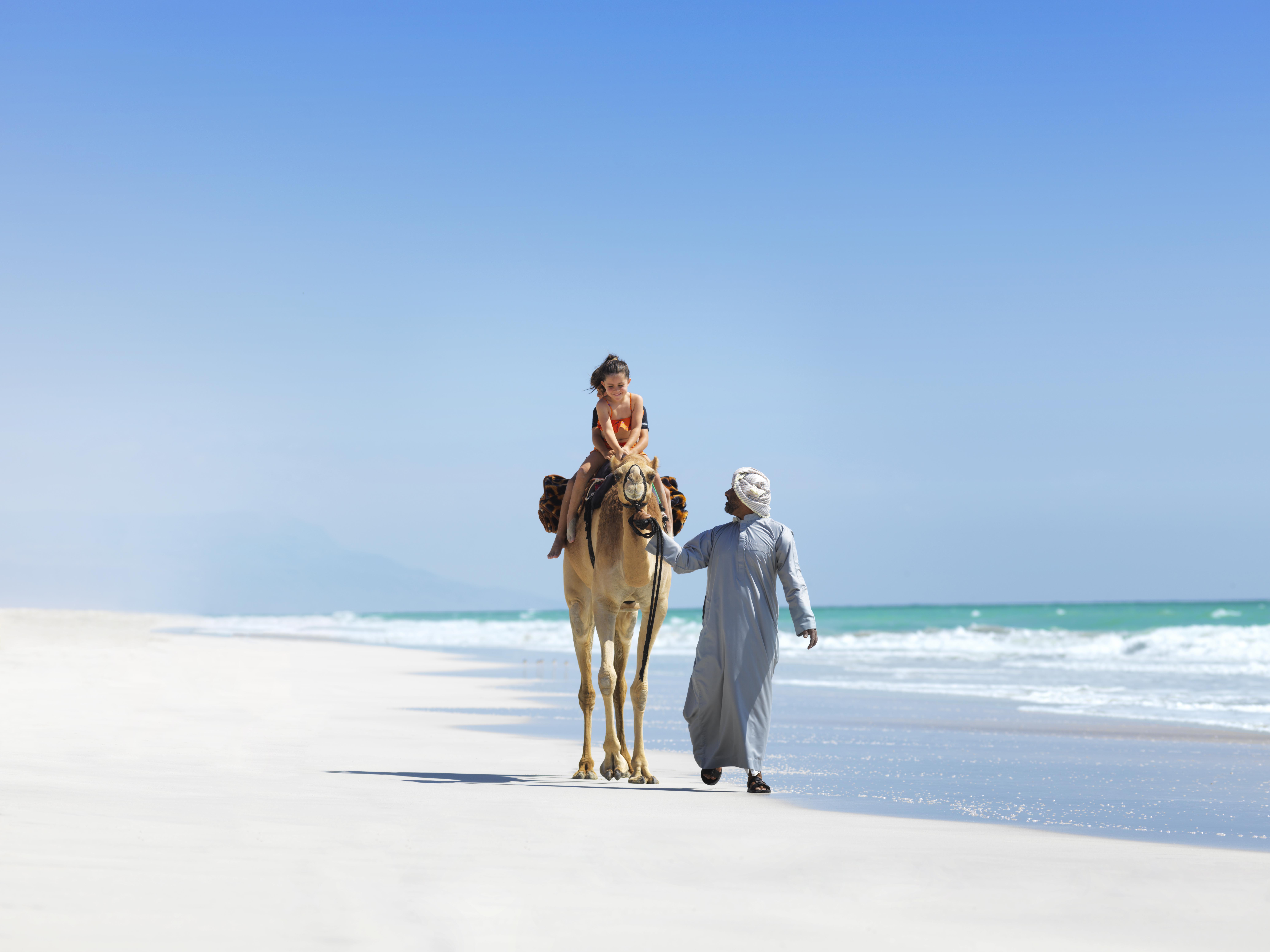 A girl enjoys a camel ride in a spectacular beach location at Al Baleed Resort Salalah by Anantara, Oman