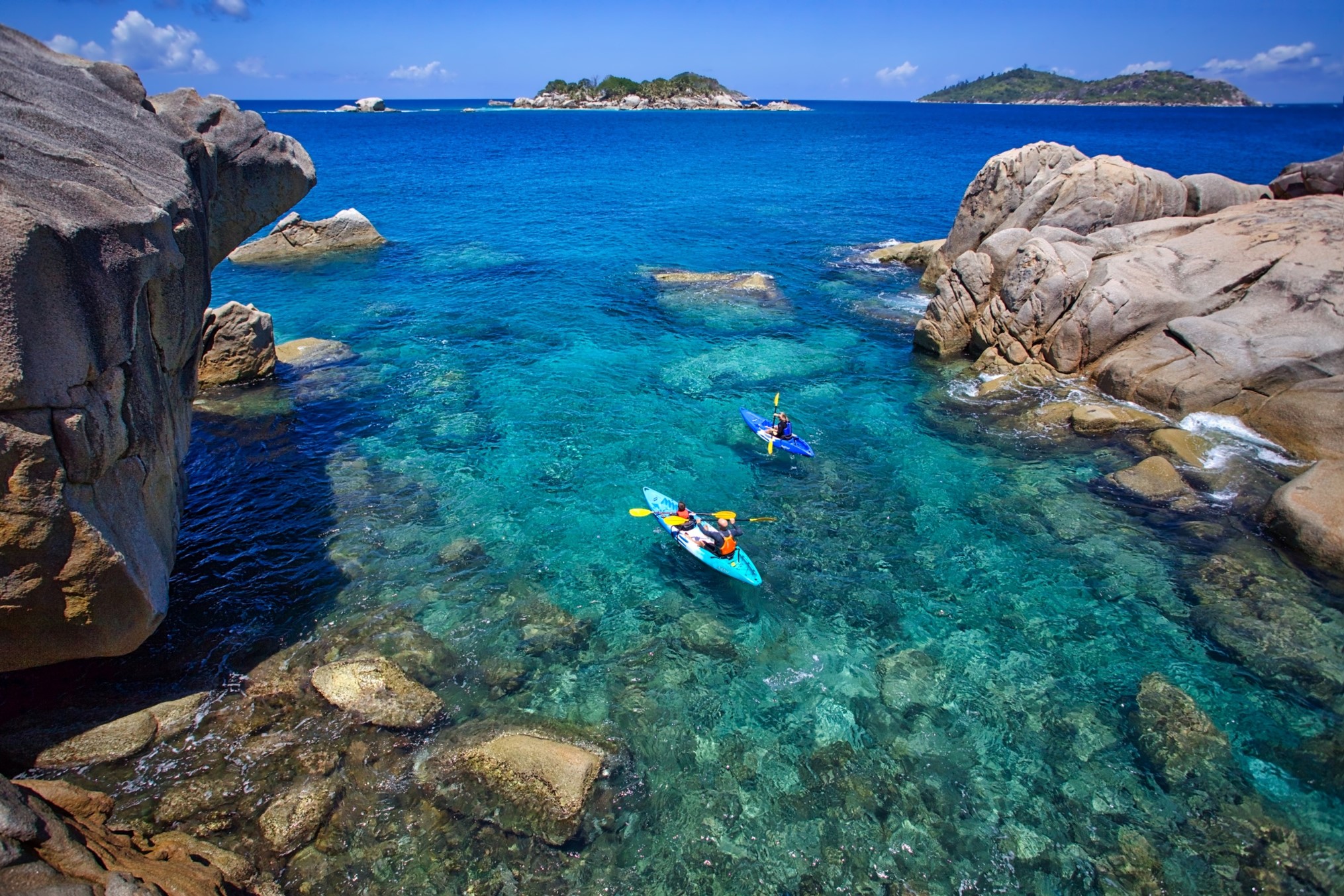 Two guests kayak over the crystal clear sea whilst exploring the various islands around Six Senses Zil Pasyon, Seychelles